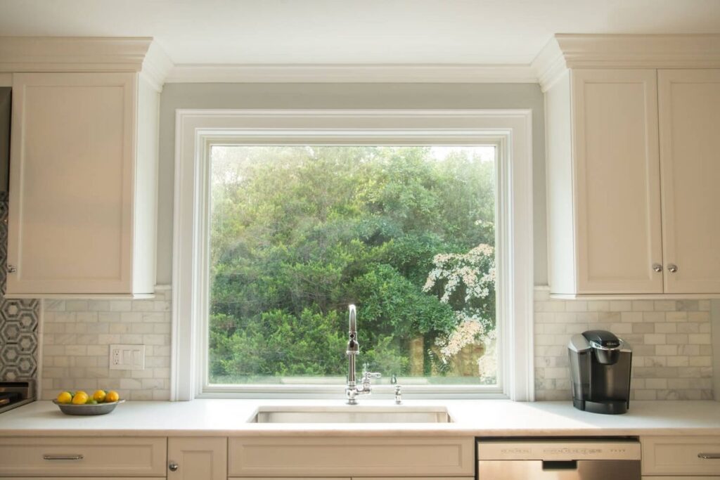 Large kitchen picture window providing bright view of backyard greenery