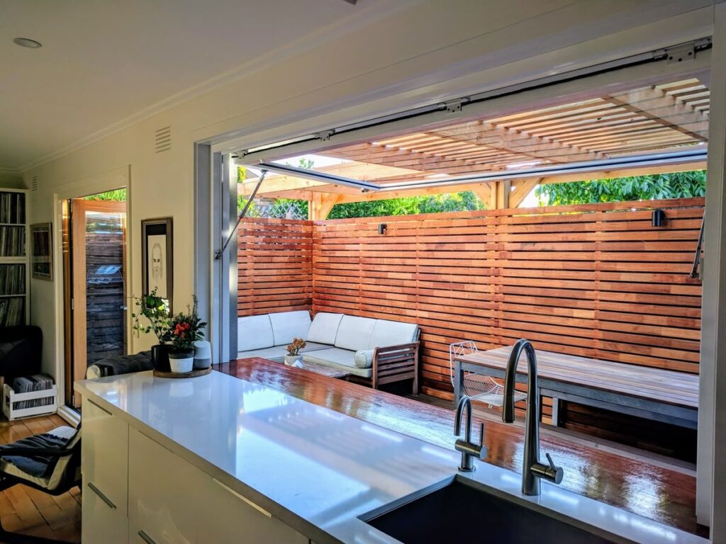 Indoor outdoor passthrough window opening to modern wooden patio